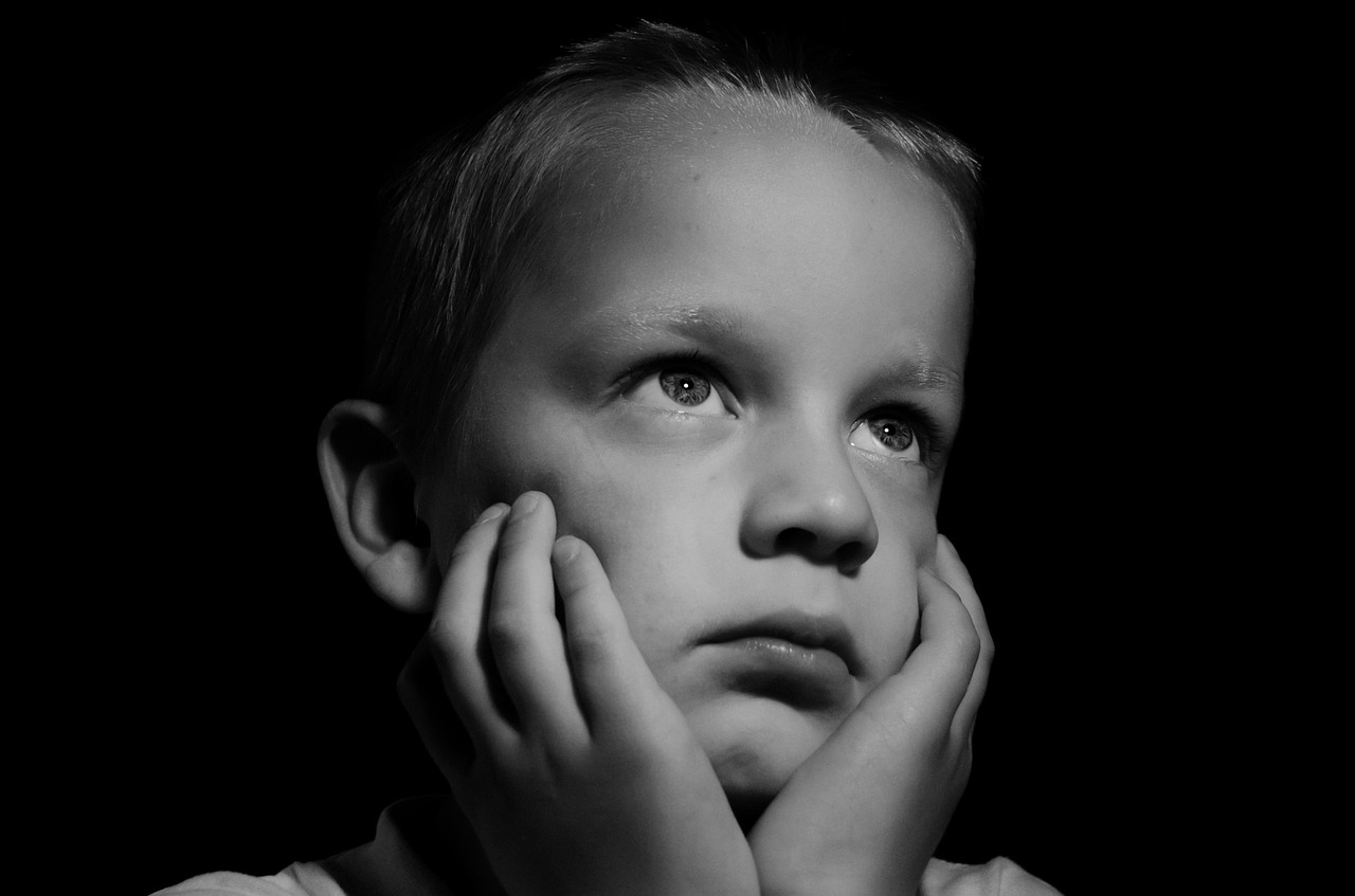 a black and white photo of a young boy, inspired by Yousuf Karsh, pexels, upset, istockphoto, grieving, blonde boy with yellow eyes