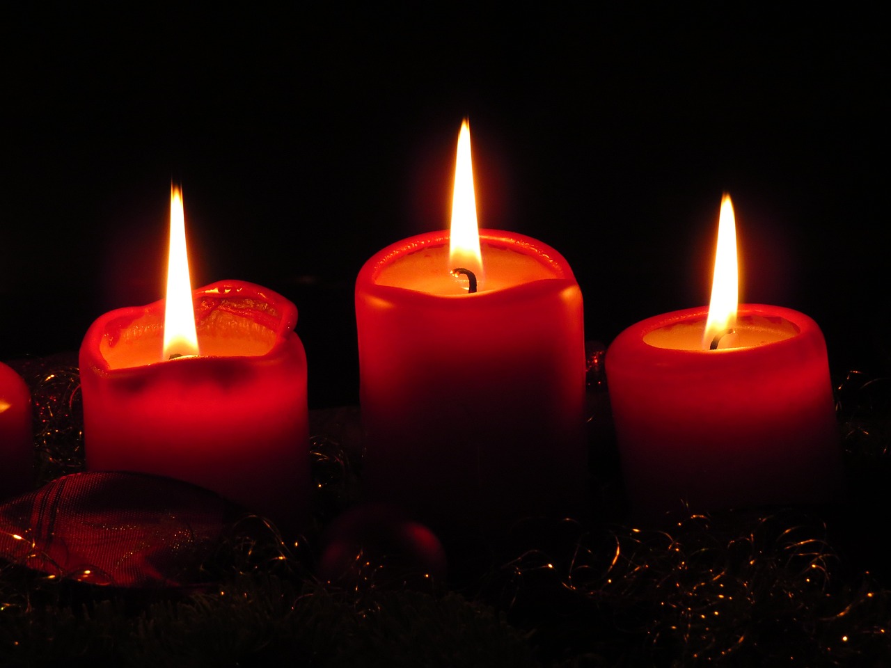 a group of lit candles sitting on top of a table, a picture, pixabay, red on black, christmas night, trio, red and yellow light