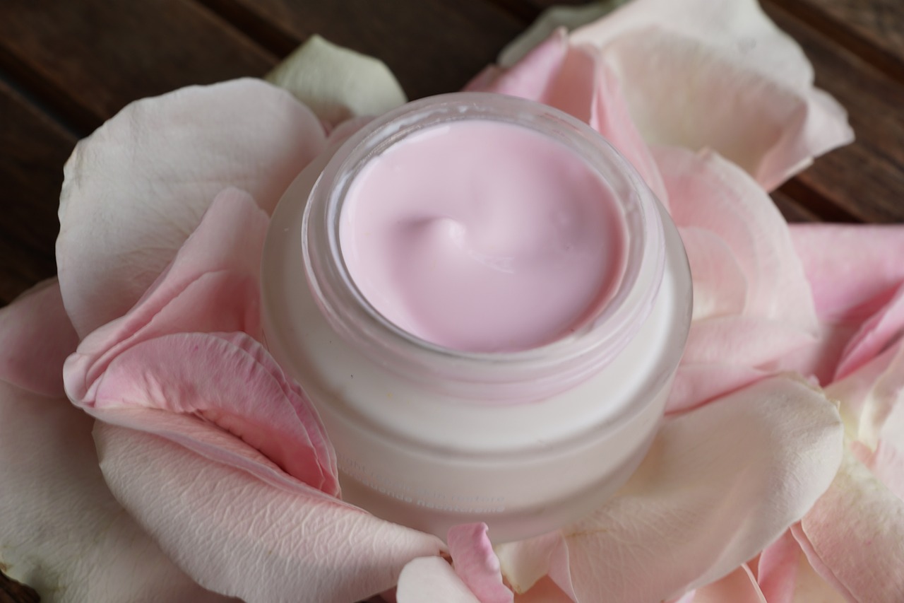 a close up of a jar of cream on a flower, by Rhea Carmi, shutterstock, flowing pink-colored silk, silicone skin, pallid skin, blush