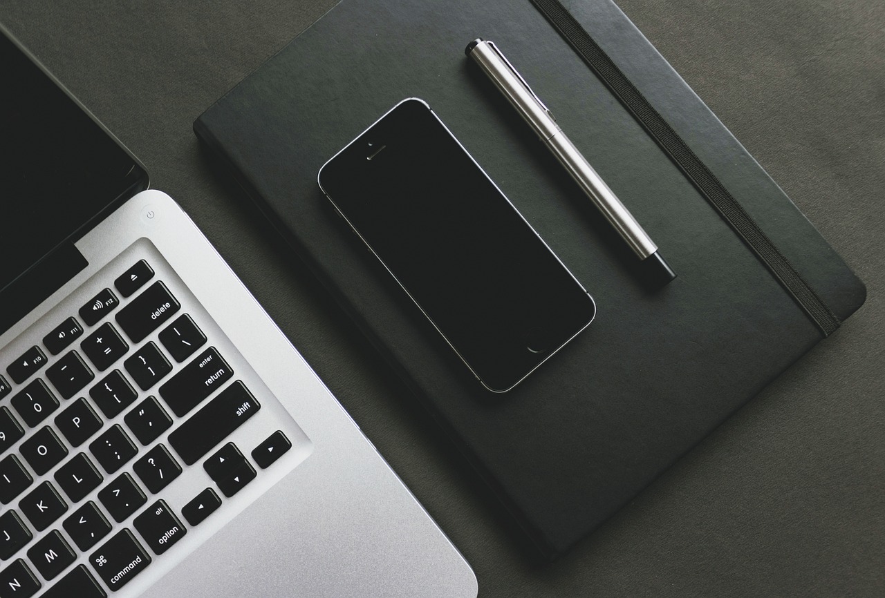 a laptop computer sitting on top of a desk next to a cell phone, by Andrei Kolkoutine, pexels, black and silver, beautiful iphone wallpaper, knolling, full - view