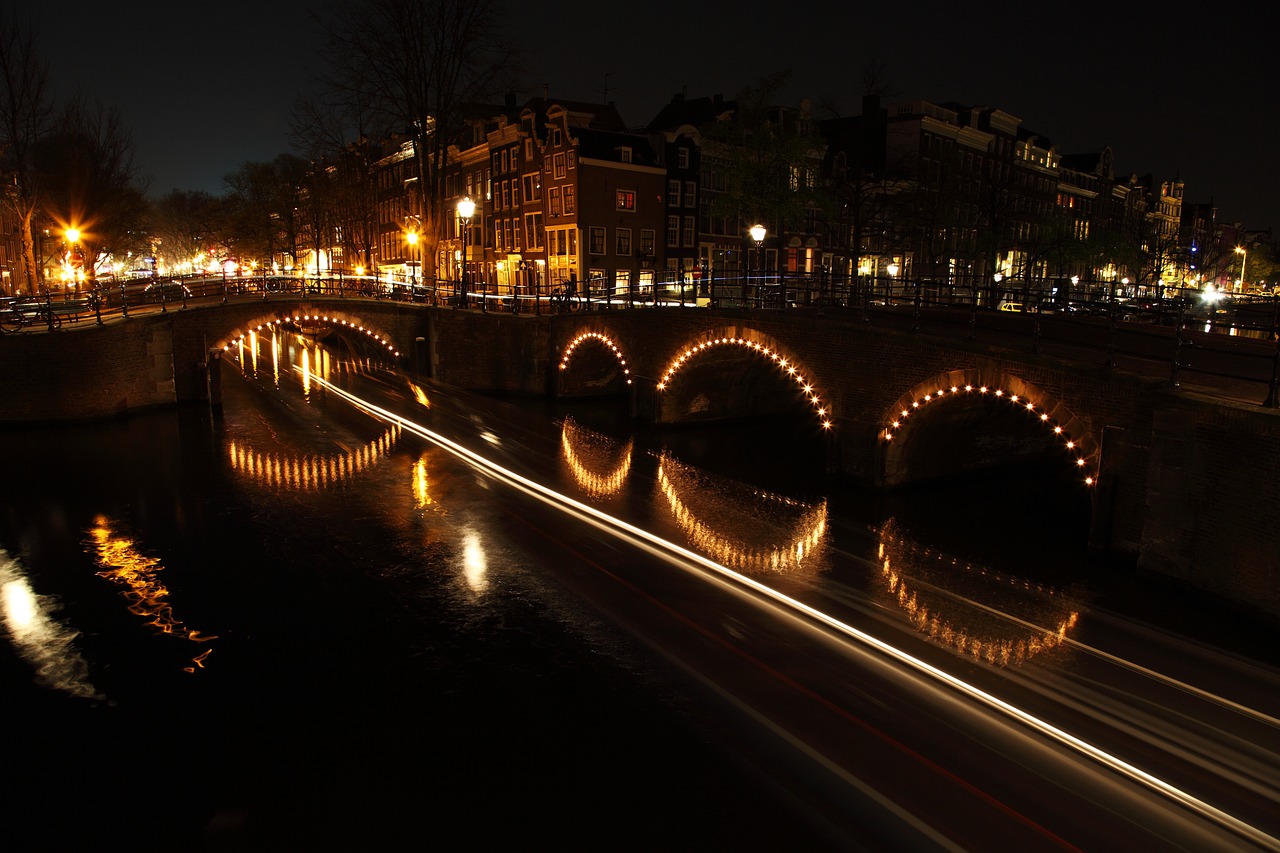 a bridge over a body of water at night, a picture, by Jacob van Utrecht, wikipedia, twisting streets, romantic light, side