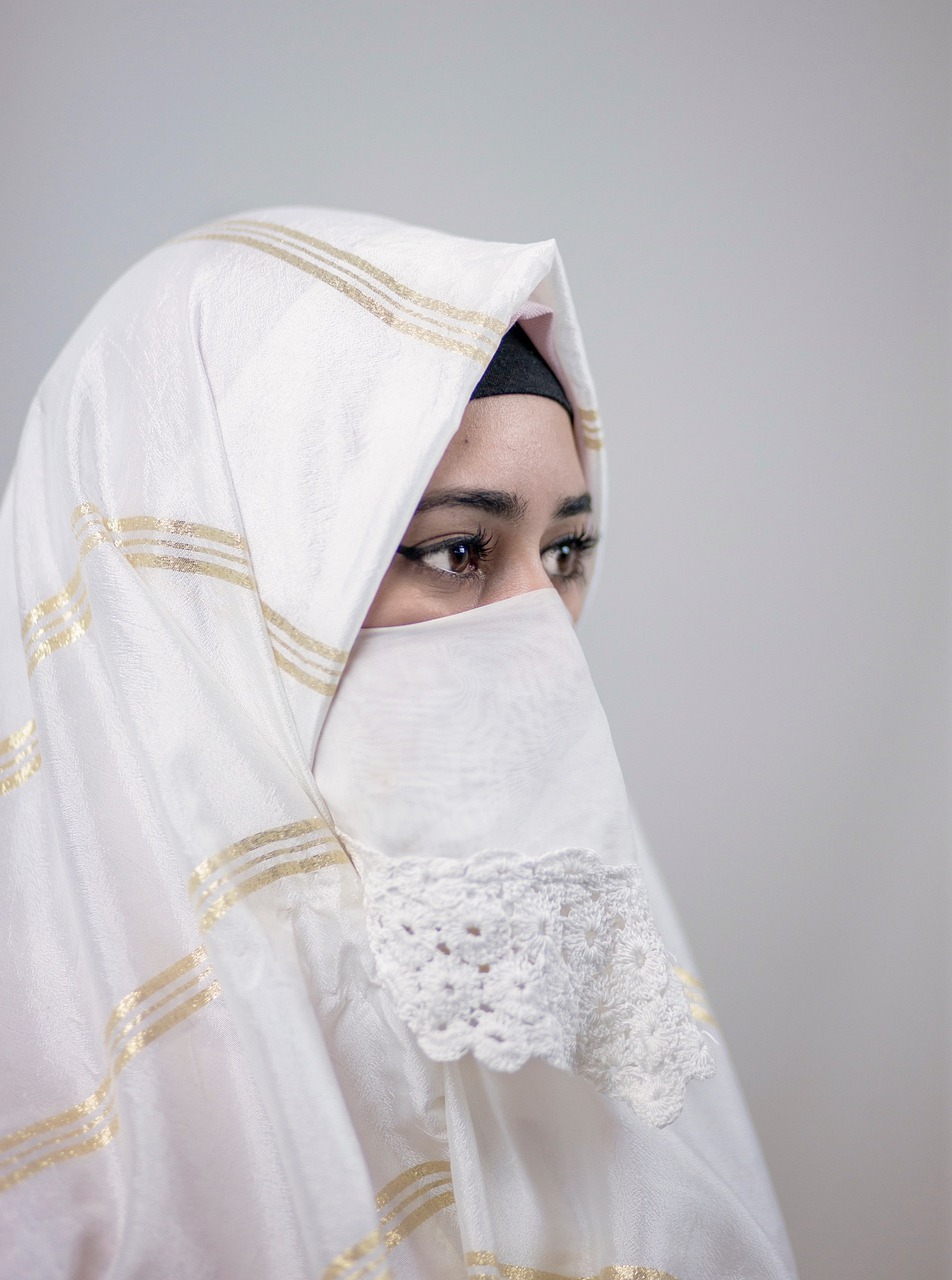 a woman with a veil covering her face, inspired by Modest Urgell, hurufiyya, with a white background, mid shot portrait, dress like taliban, white cloth