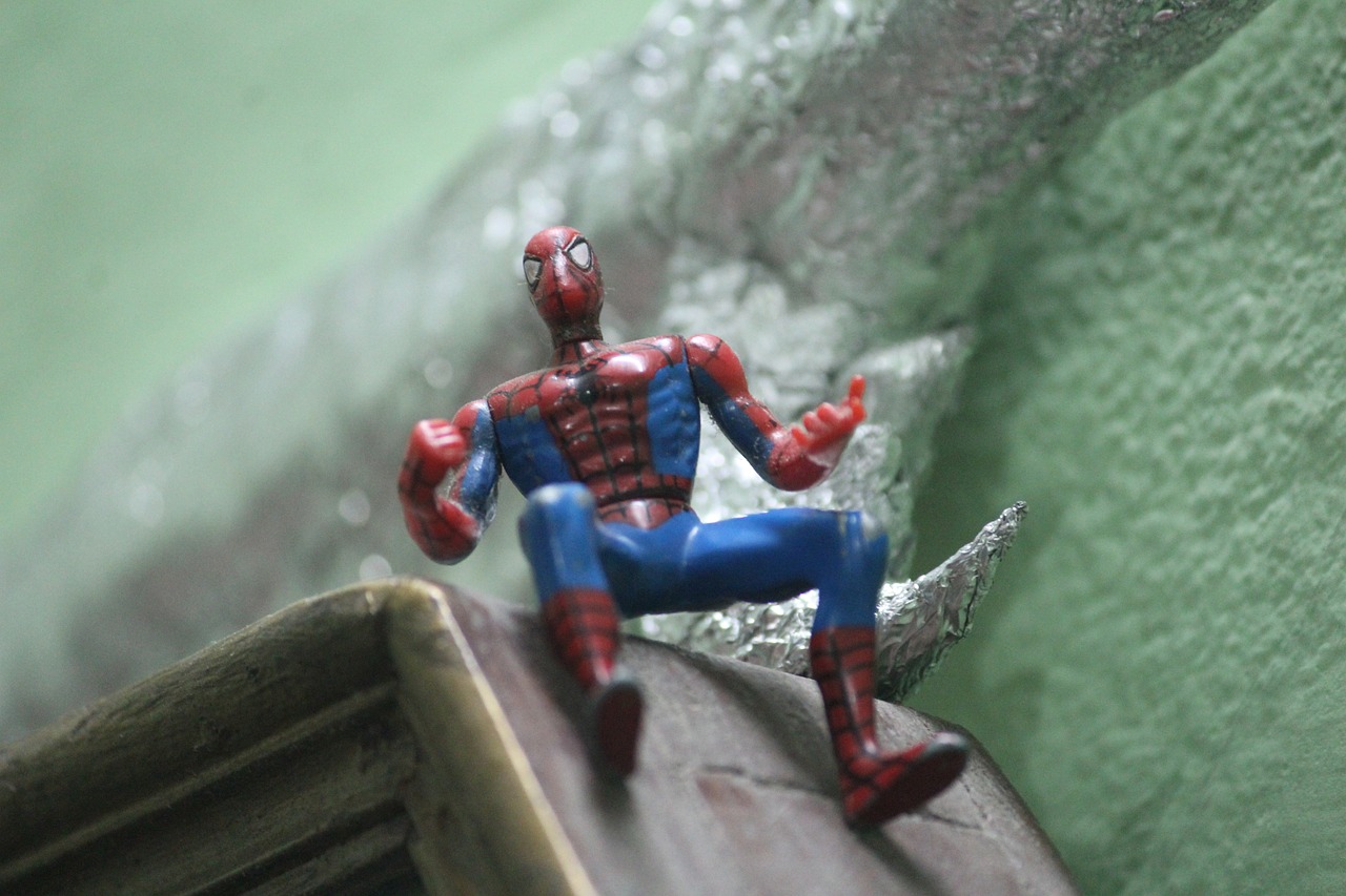 a close up of a toy spider - man sitting on a ledge, a picture, 1/400, character is covered in liquid, heroic posture, 50mm photo
