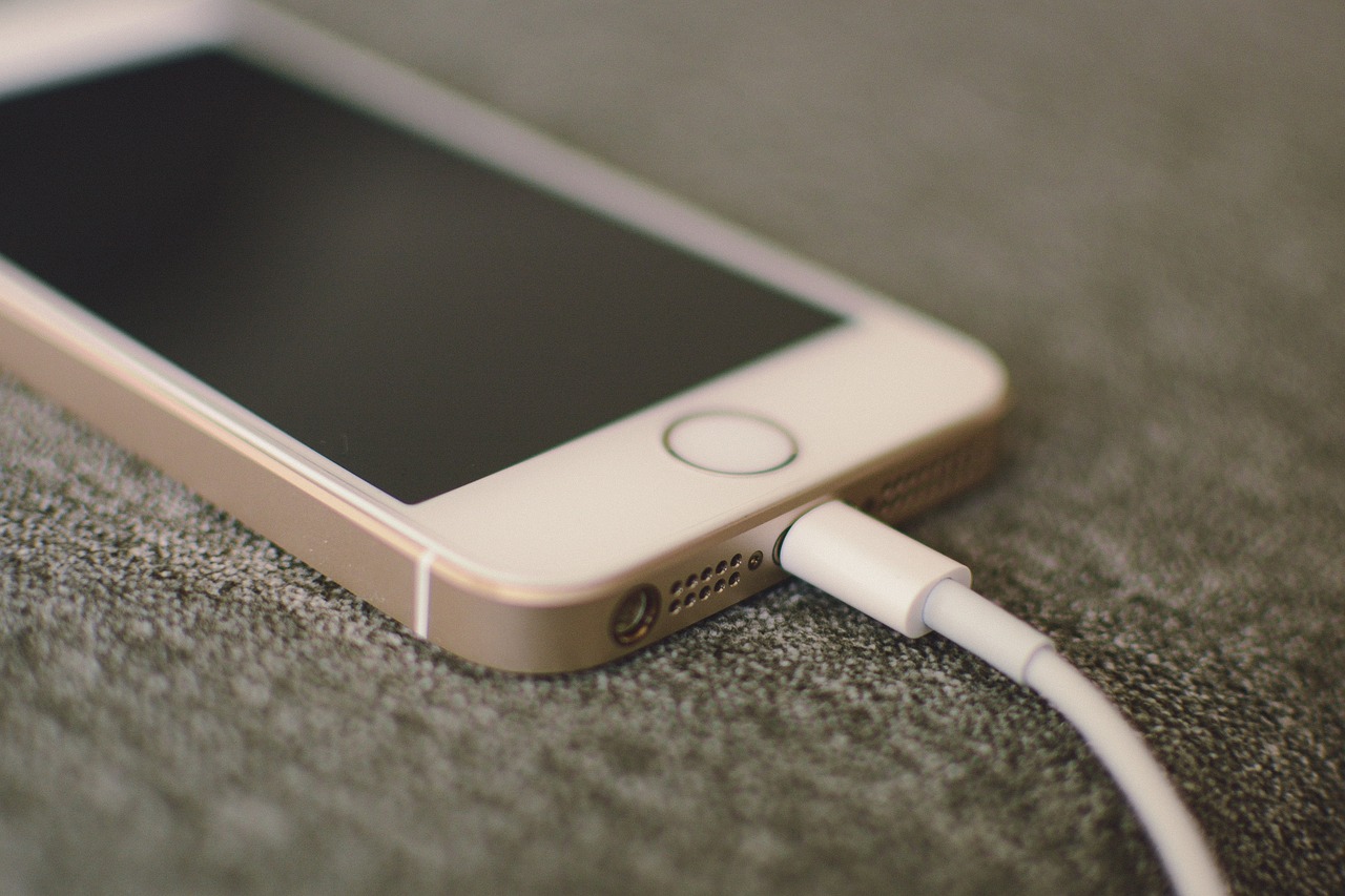 a close up of a cell phone connected to a charger, by Edward Corbett, pexels, iphone video, lying down, in 2 0 1 5, subtle detailing