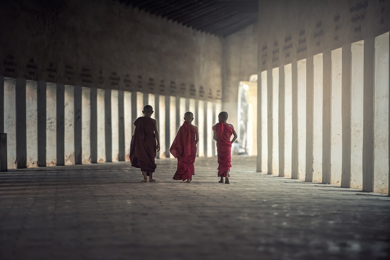 a group of people walking down a hallway, a picture, inspired by Steve McCurry, minimalism, buddhist monk, pillars, boys, filtered evening light