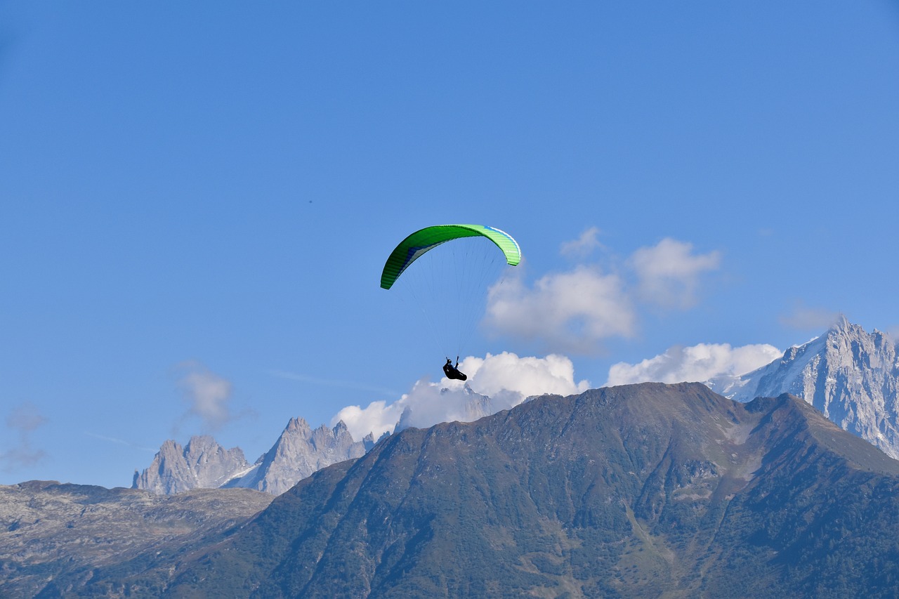 a person that is in the air with a parachute, a picture, by Erwin Bowien, shutterstock, chamonix, a green, seen from a distance, with wings