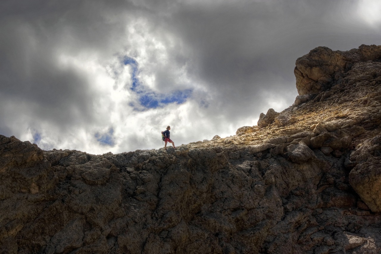 a person standing on top of a rocky hill, a picture, by Andrew Domachowski, figuration libre, light and clouds, dolomites, be running up that hill, new mexico