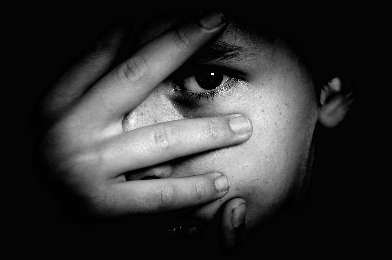 a close up of a person holding their hand to their face, a black and white photo, by irakli nadar, pexels, black eyed kids, self - portrait!!!!, looking scared, an eye