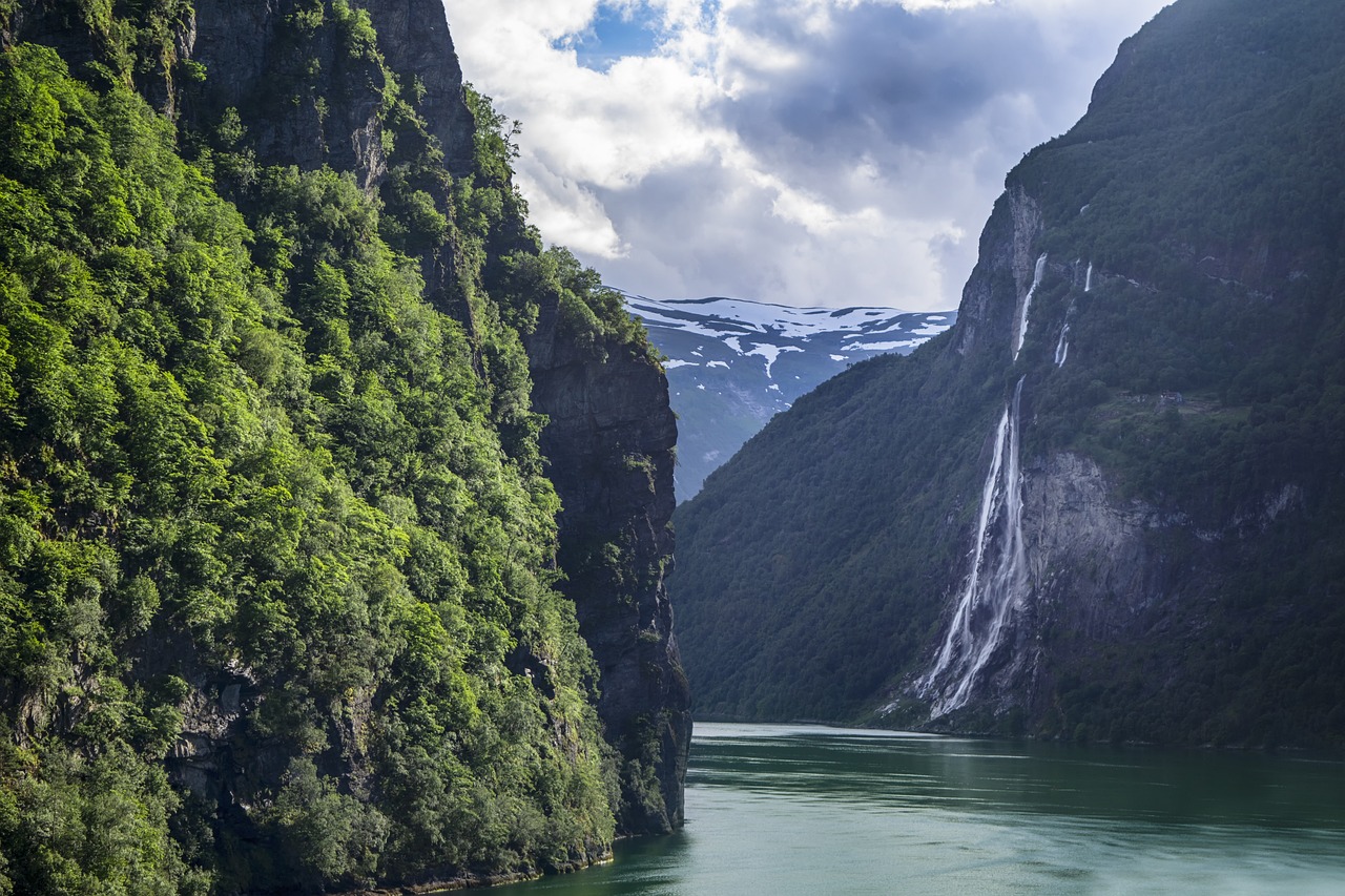 a body of water with a waterfall in the background, by Harry Haenigsen, shutterstock, fjord, photo taken from a boat, lush valley, by joseph binder