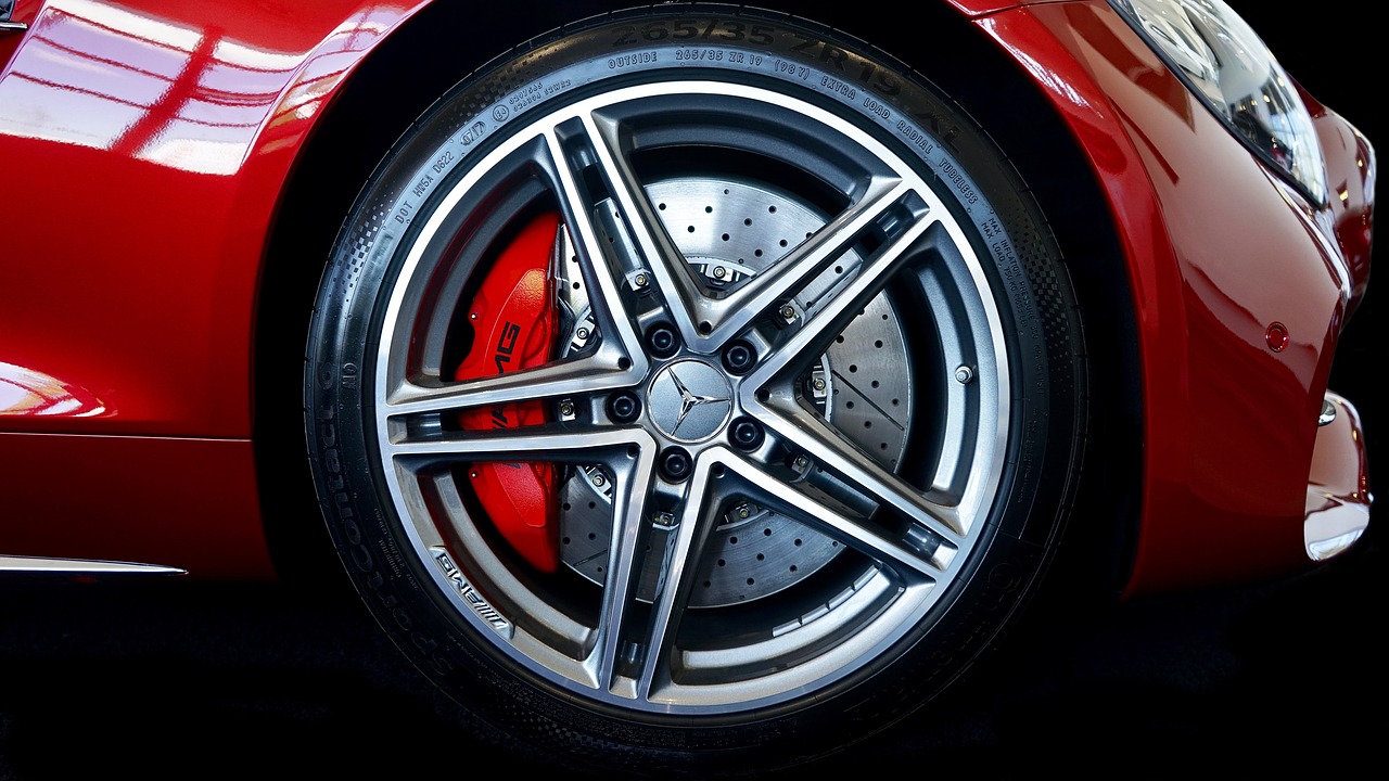 the front wheel of a red sports car, a picture, by Thomas Häfner, pexels, photorealism, detailed alloy wheels, red white and black color scheme, advert, mercedez benz