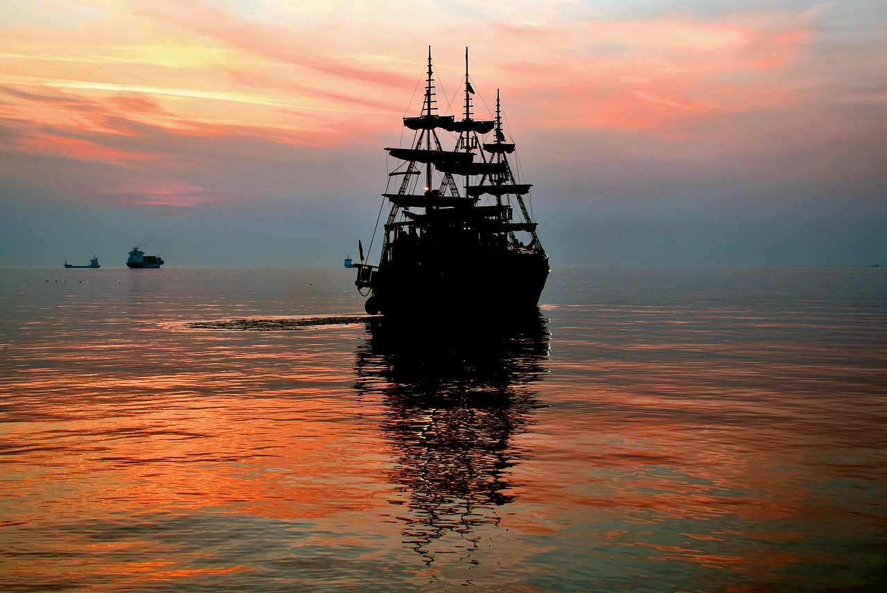 a large boat floating on top of a body of water, a photo, by Tom Carapic, shutterstock, romanticism, pirate setting, black silhouette, nice colors, full frame shot