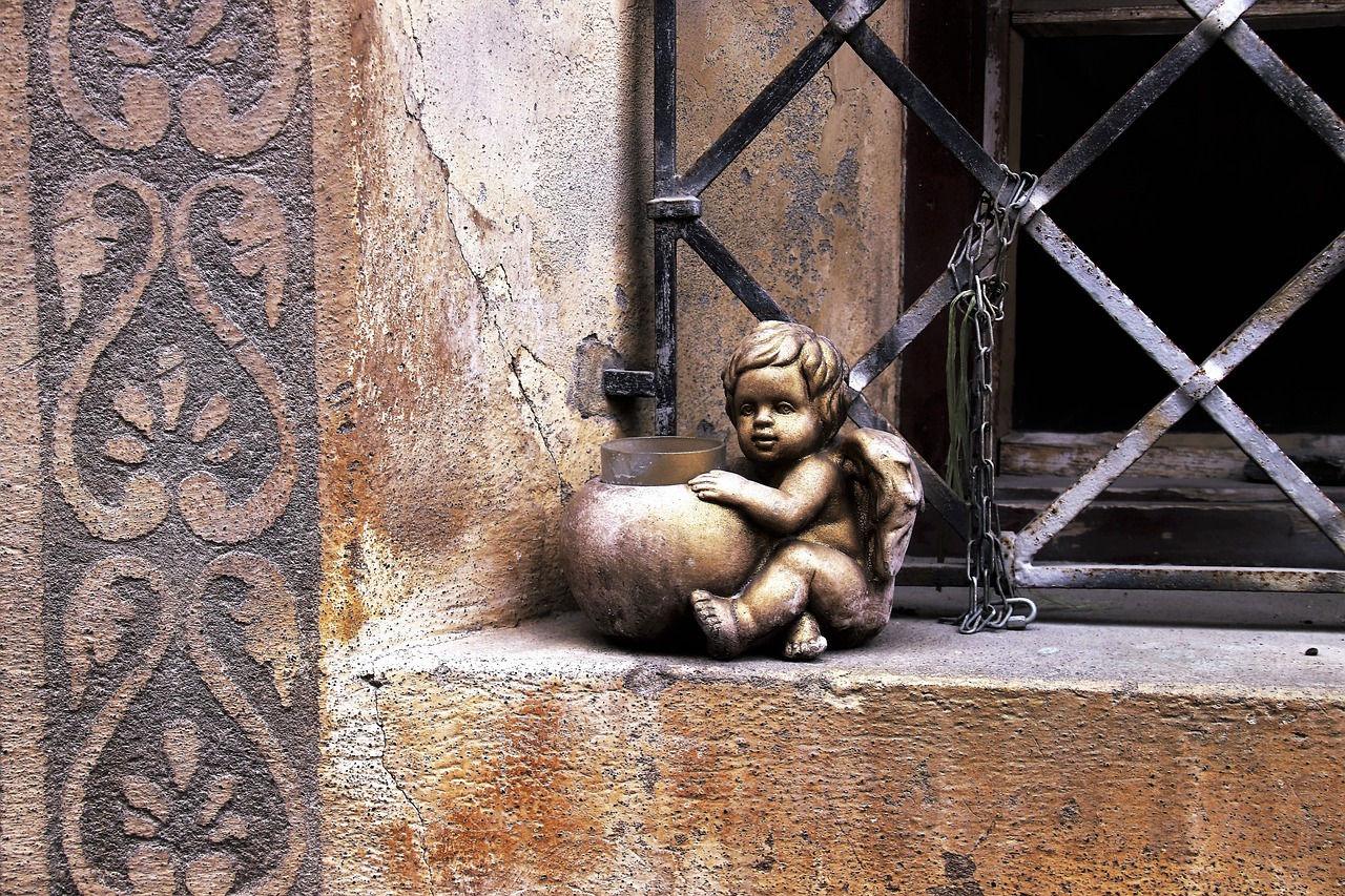 a statue of a little boy sitting on a ledge, inspired by Taddeo Gaddi, street art, toy photo, fetus, angels, window