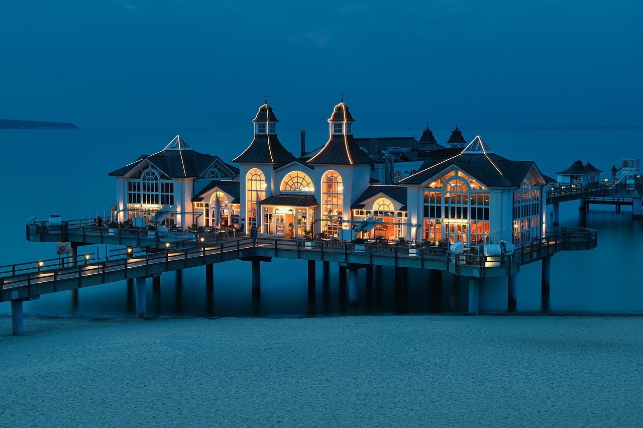 a pier in the middle of a body of water, art nouveau, taverns nighttime lifestyle, beachfront mansion, prussia, restaurant exterior photography