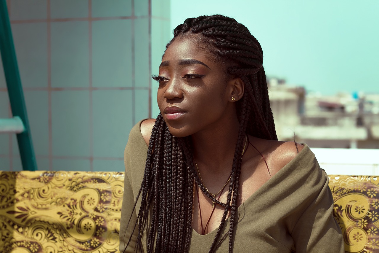 a woman with long braids sitting on a couch, a portrait, inspired by Ras Akyem, trending on pexels, on a rooftop, matte detailed photo, black teenage girl, on a bright day