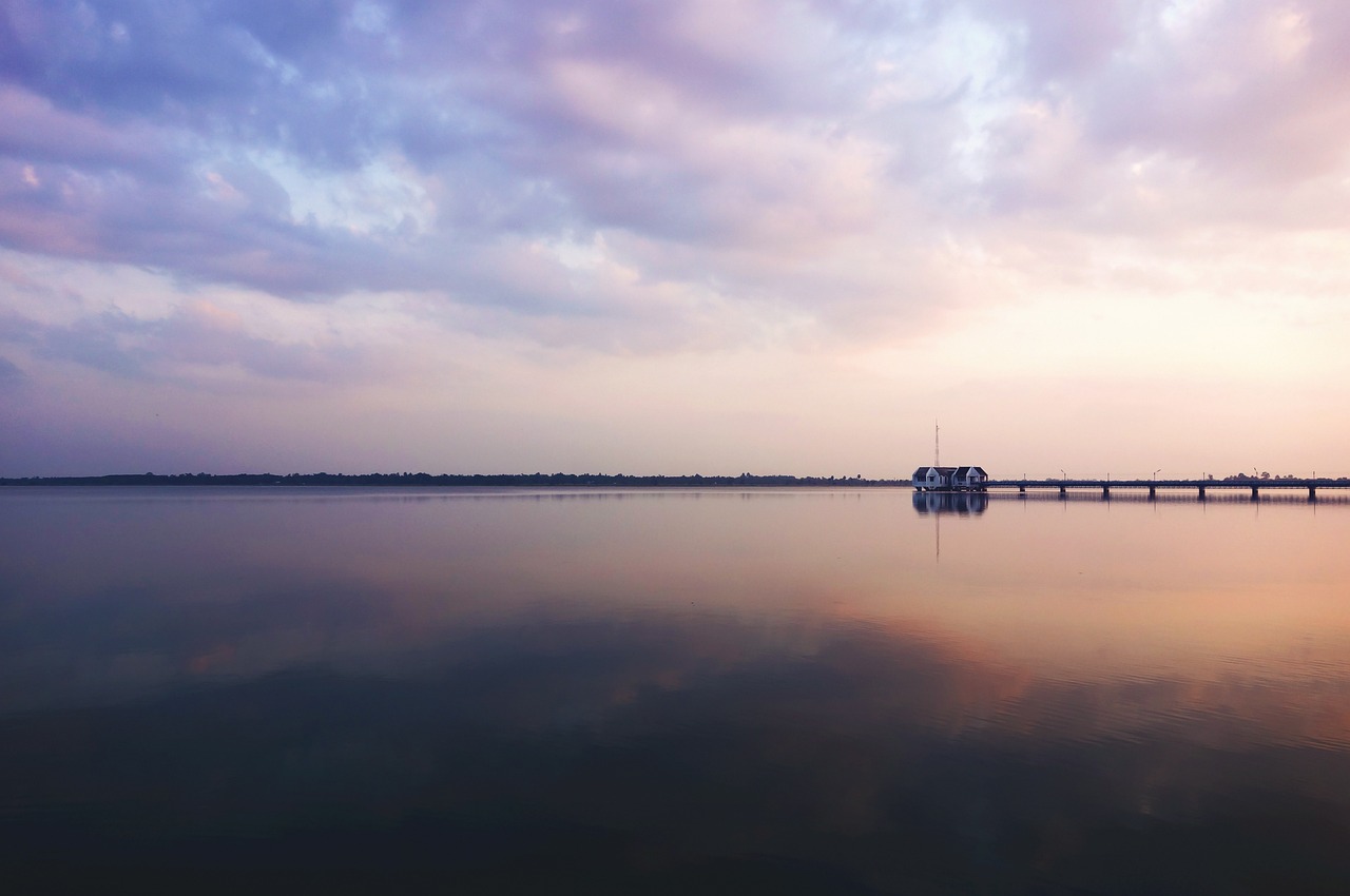 a boat floating on top of a lake under a cloudy sky, a picture, minimalism, sunset photo, wide shot photo, near a jetty, panoramic photography