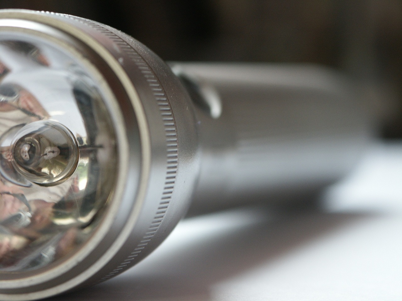a close up of a flashlight on a table, a picture, pexels, photorealism, silver, very sharp photo, bright rim light, screw