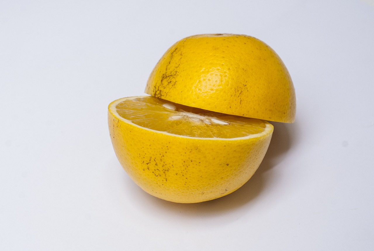 an orange cut in half on a white surface, a picture, by Richard Carline, yellow, focus stacking, covered, half moon