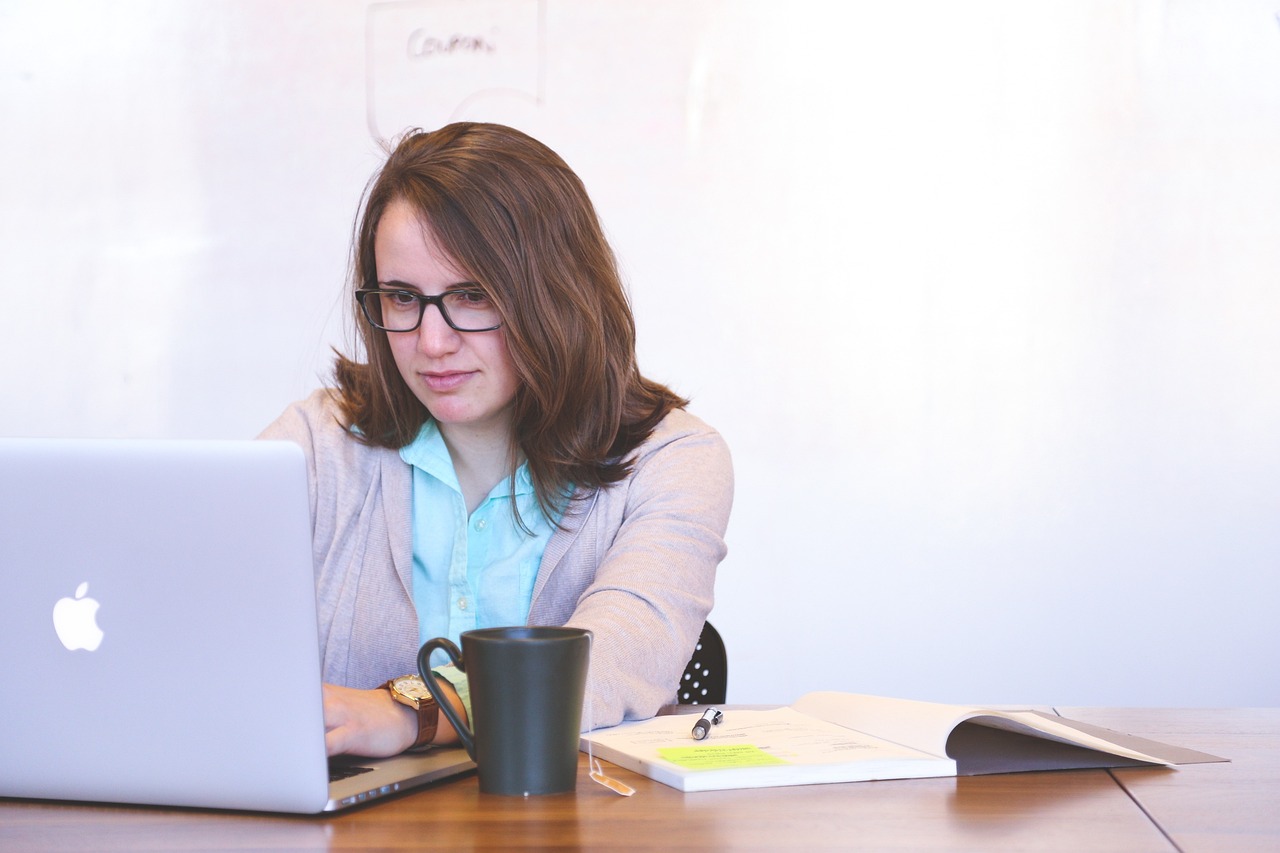 a woman sitting in front of a laptop computer, pexels, realism, working in an office, istockphoto, caucasian, girl with glasses