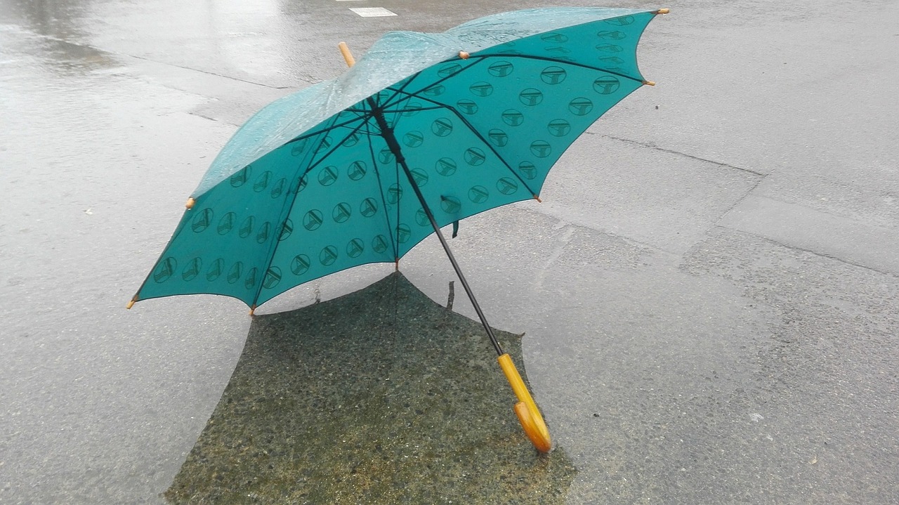 a blue umbrella sitting on top of a wet sidewalk, a photo, by Géza Udvary, auto-destructive art, with teal clothes, pattern, coffee, rain sensor