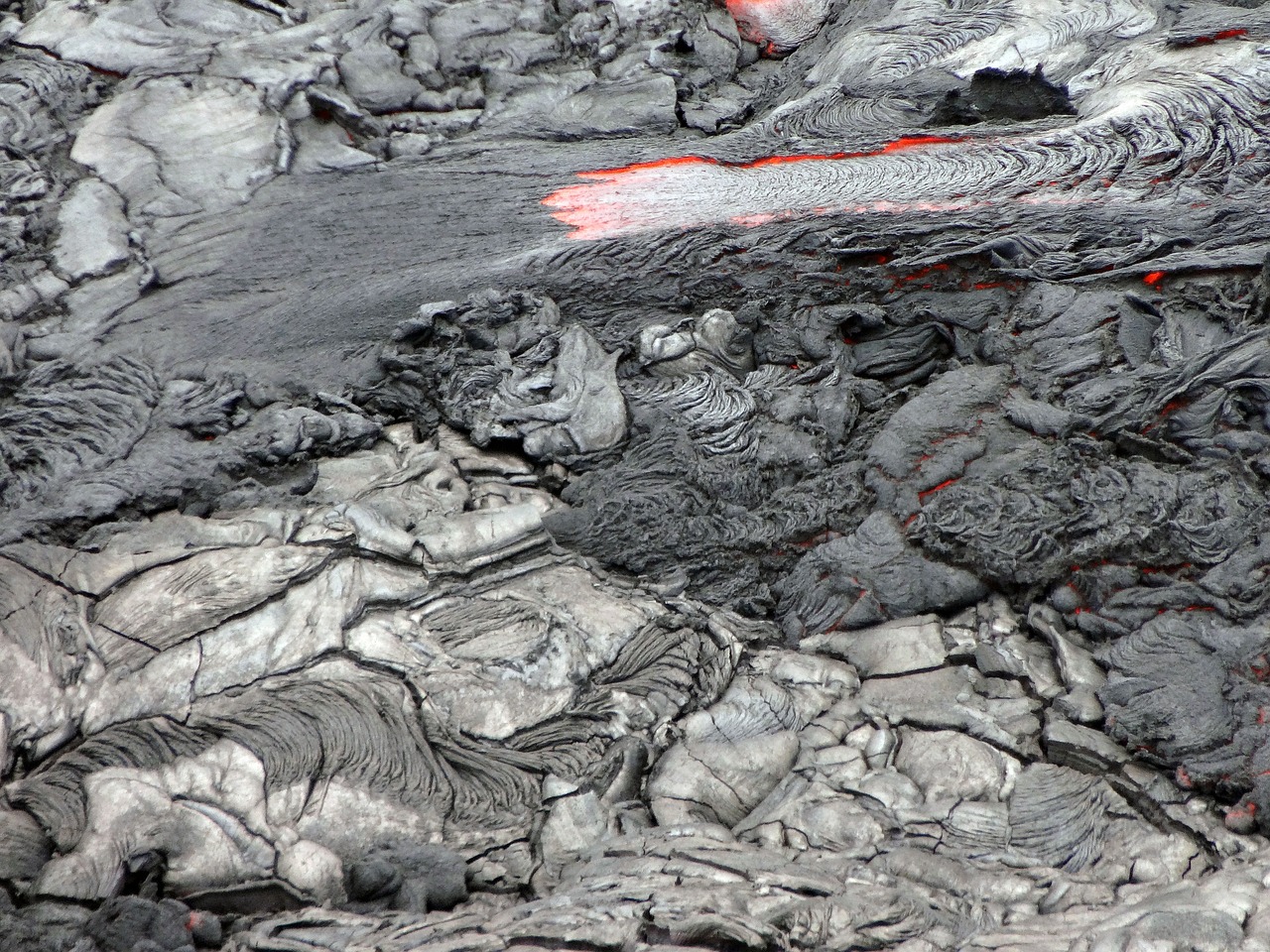 a close up of some rocks and lava, by Rudolf Schlichter, flickr, camera looking down into the maw, slightly red, some of the blacktop is showing, shaded