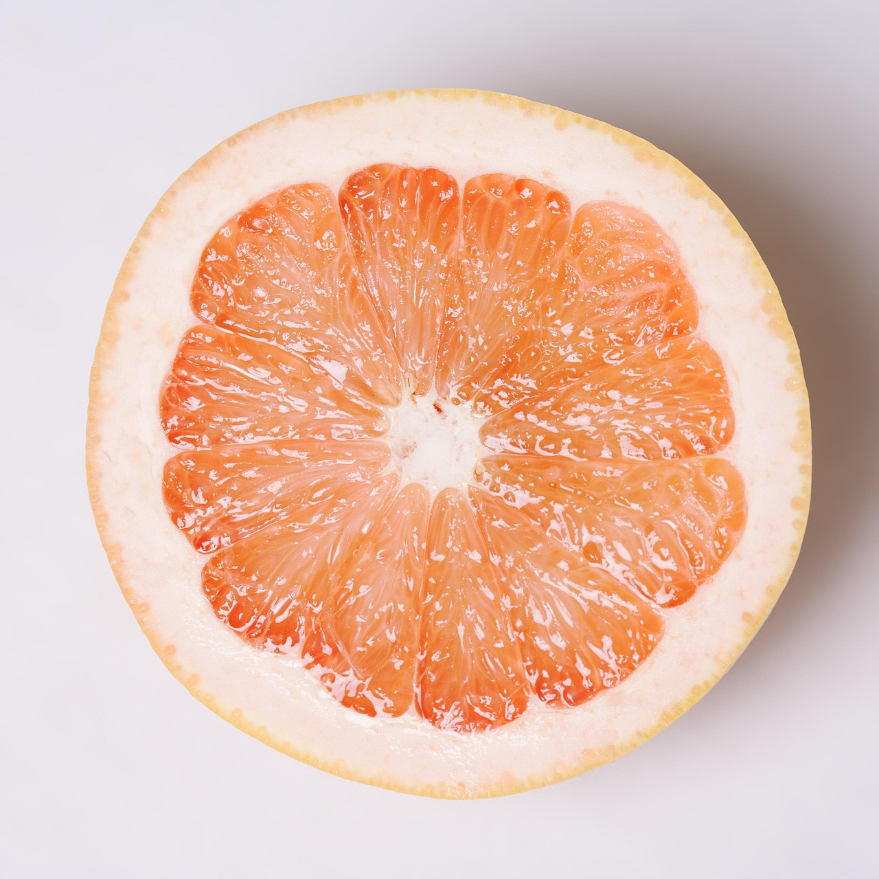 a grapefruit cut in half on a white surface, a picture, by Hiroyuki Tajima, shutterstock, sōsaku hanga, view from bottom to top, half body photo, rice, stock photo
