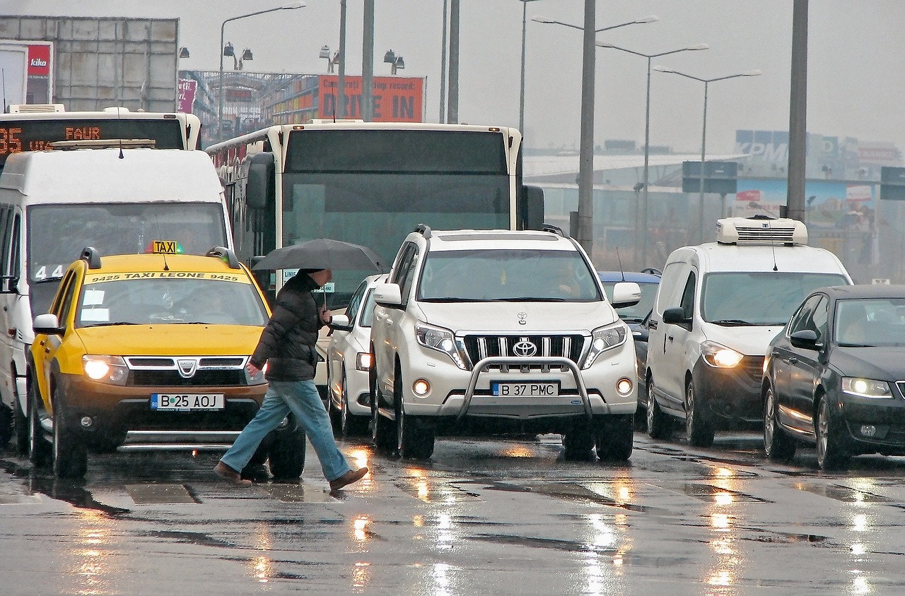 a person crossing the street in the rain with an umbrella, a picture, by Martin Benka, parked cars, istanbul, ( ( ( buses, video