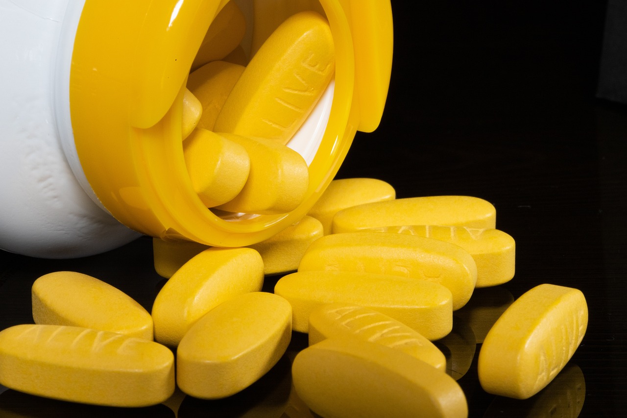 a close up of a bottle of pills on a table, by Juan O'Gorman, shutterstock, antipodeans, bolts of bright yellow fish, on black background, shades of yellow, 3 4 5 3 1