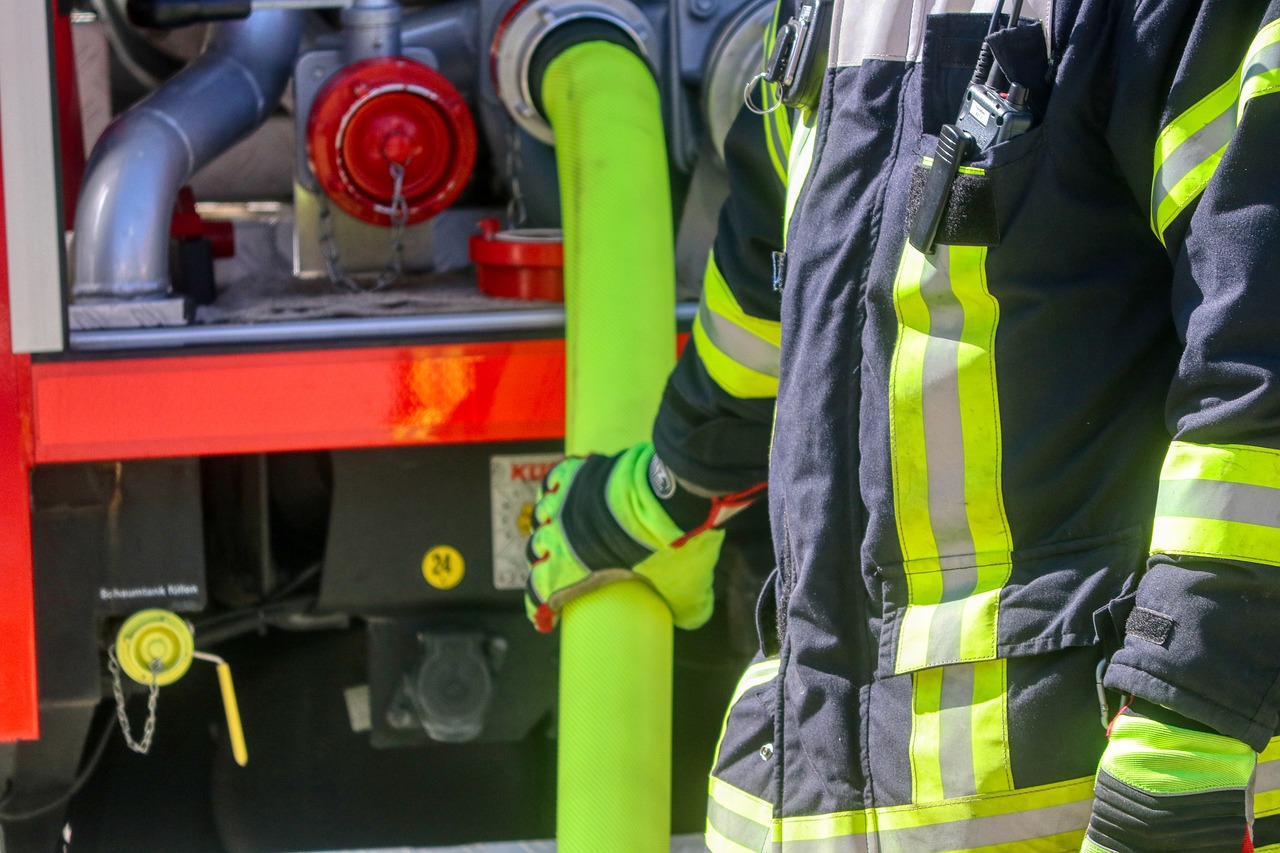 a firefighter standing in front of a fire truck, by Daniel Lieske, shutterstock, figuration libre, green neon details, yellow latex gloves, water pipe, detailed close up shot