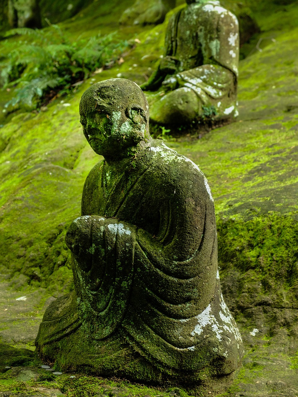 a couple of statues sitting on top of a moss covered ground, inspired by Kaigetsudō Anchi, very very well detailed image, holy man looking at ground, muted green, the buddha