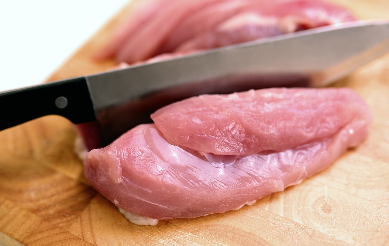 a close up of meat on a cutting board with a knife, by Josetsu, shutterstock, sōsaku hanga, chicken feathers, soft chin, very sharp photo