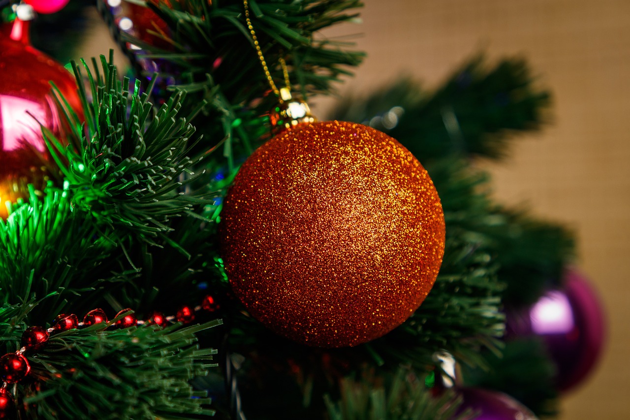 a close up of a christmas ornament on a tree, by Aleksander Gierymski, shutterstock, realism, dark orange, stock photo, glitter, 7 0 mm photo