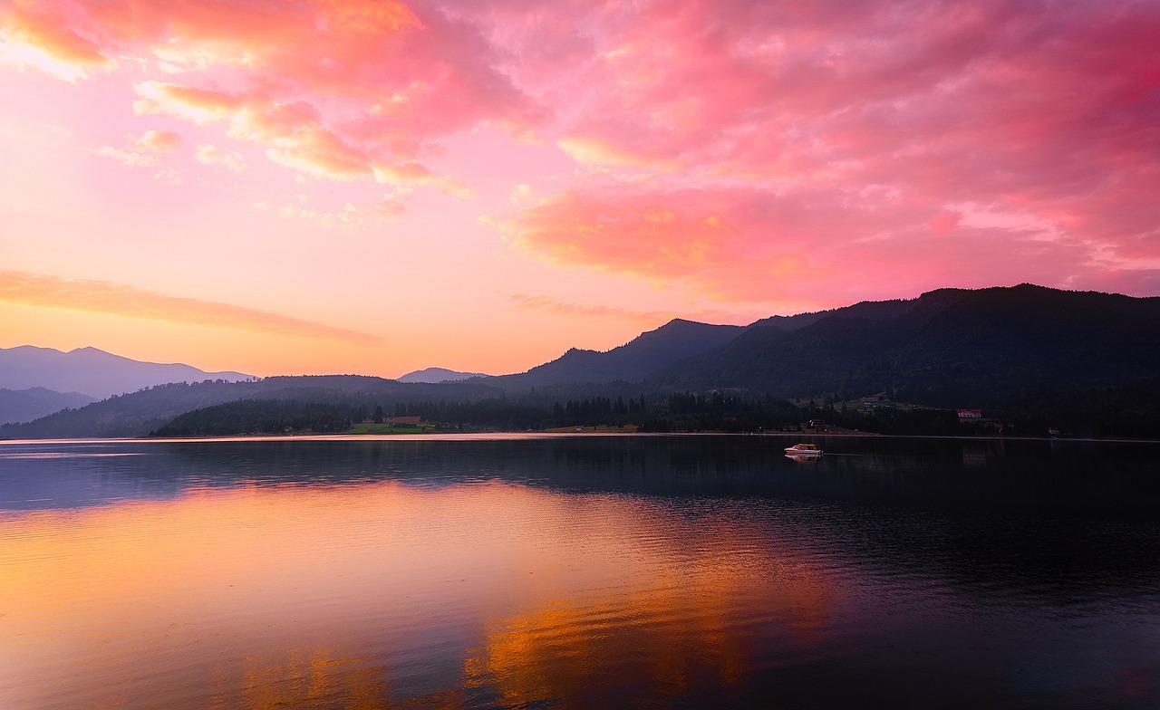 a boat floating on top of a lake at sunset, flickr, whistler, pink and orange colors, mountain sunrise, wide river and lake