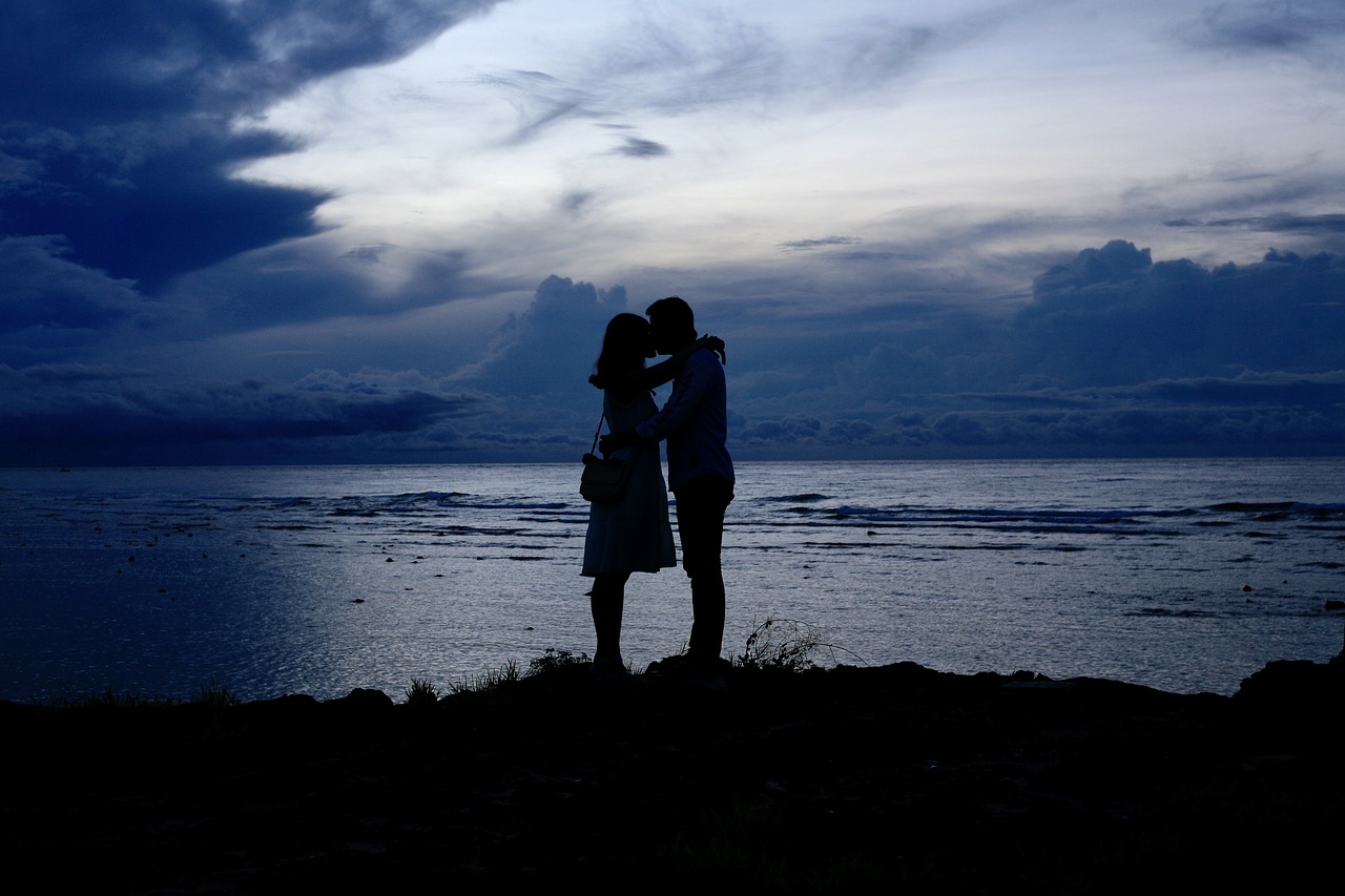 a couple of people standing next to each other on a beach, a picture, by Tadashige Ono, romanticism, couple kissing, harsh flash photo, afp, beautiful scenery