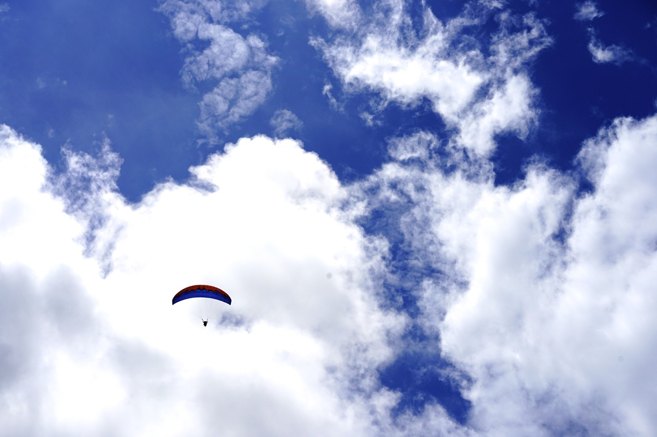a paraglider flying through a cloudy blue sky, a photo, minimalism, surrounded in clouds and light, flash photo