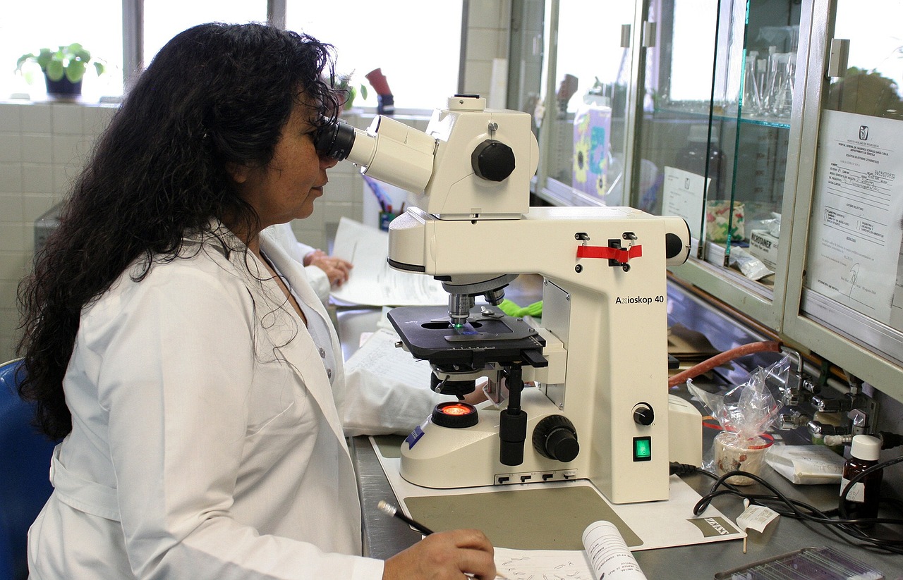 a woman in a lab coat looking through a microscope, a picture, peruvian, latina, italian, research complex