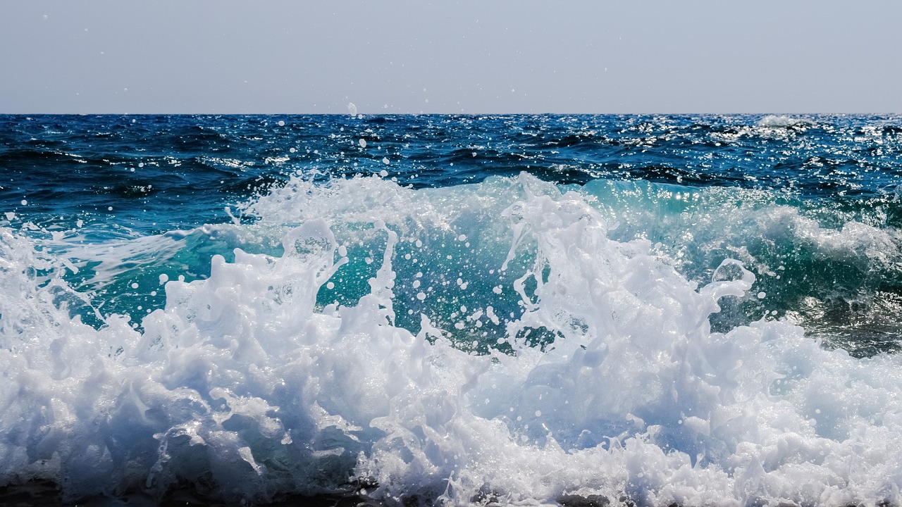 a man riding a wave on top of a surfboard, a picture, shutterstock, azure waves of water, mediterranean beach background, foamy bubbles, wallpaper - 1 0 2 4