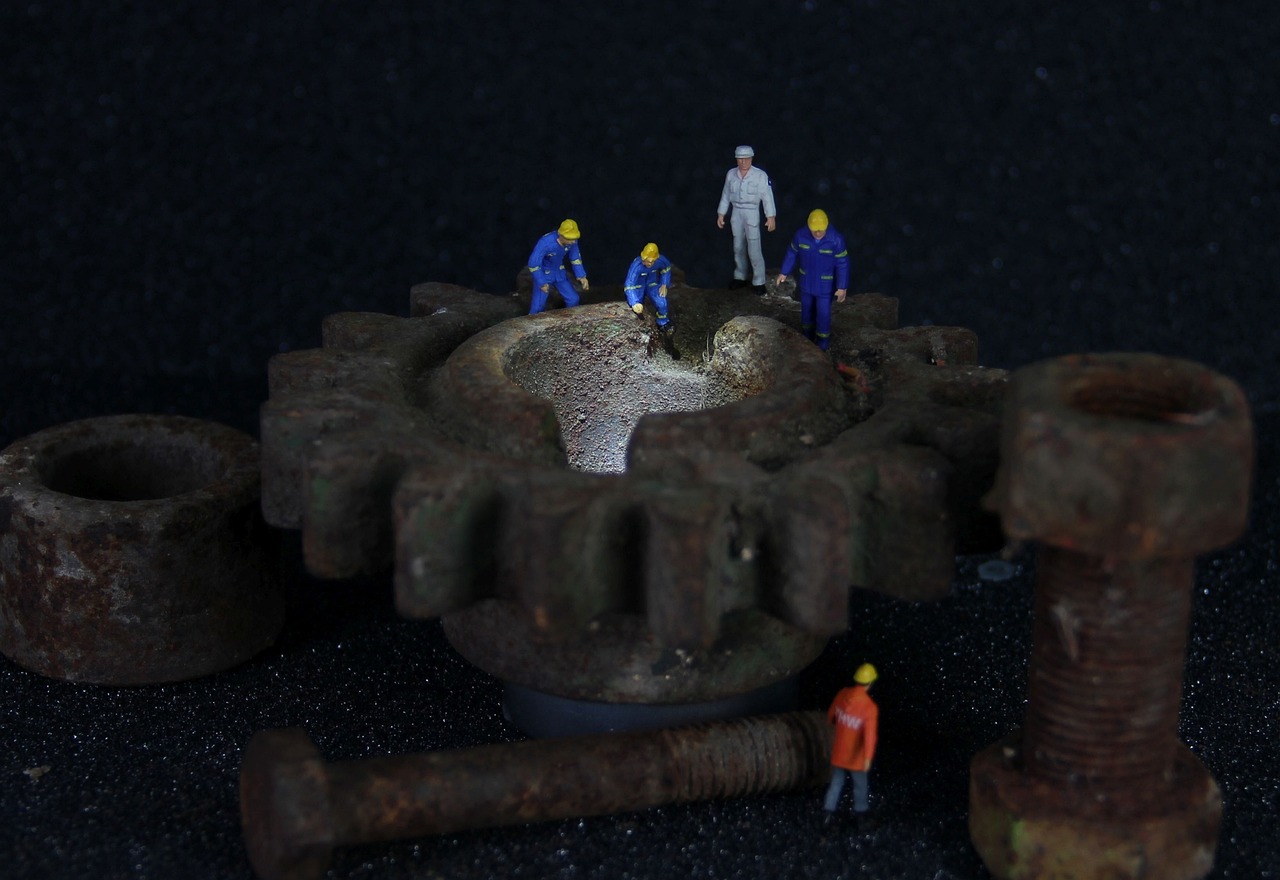 a group of men standing on top of a metal gear, a tilt shift photo, flickr, assemblage, ((gears)), a photograph of a rusty, safe for work, detail on scene