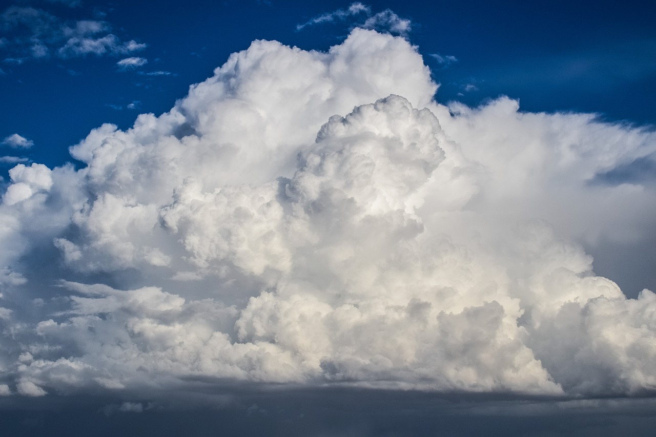 a large cloud in the middle of a blue sky, by Arnie Swekel, ultra detailed storm clouds, large white clouds, above the clouds, heavy rain from thick clouds
