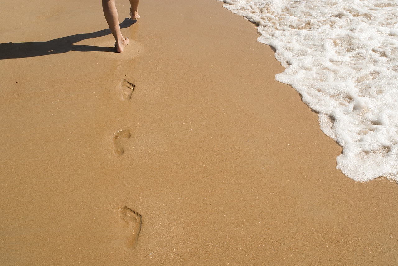 a person walking on a beach with footprints in the sand, a picture, by John Clayton Adams, shutterstock, side view of her taking steps, maui, usa-sep 20, 30 year old man