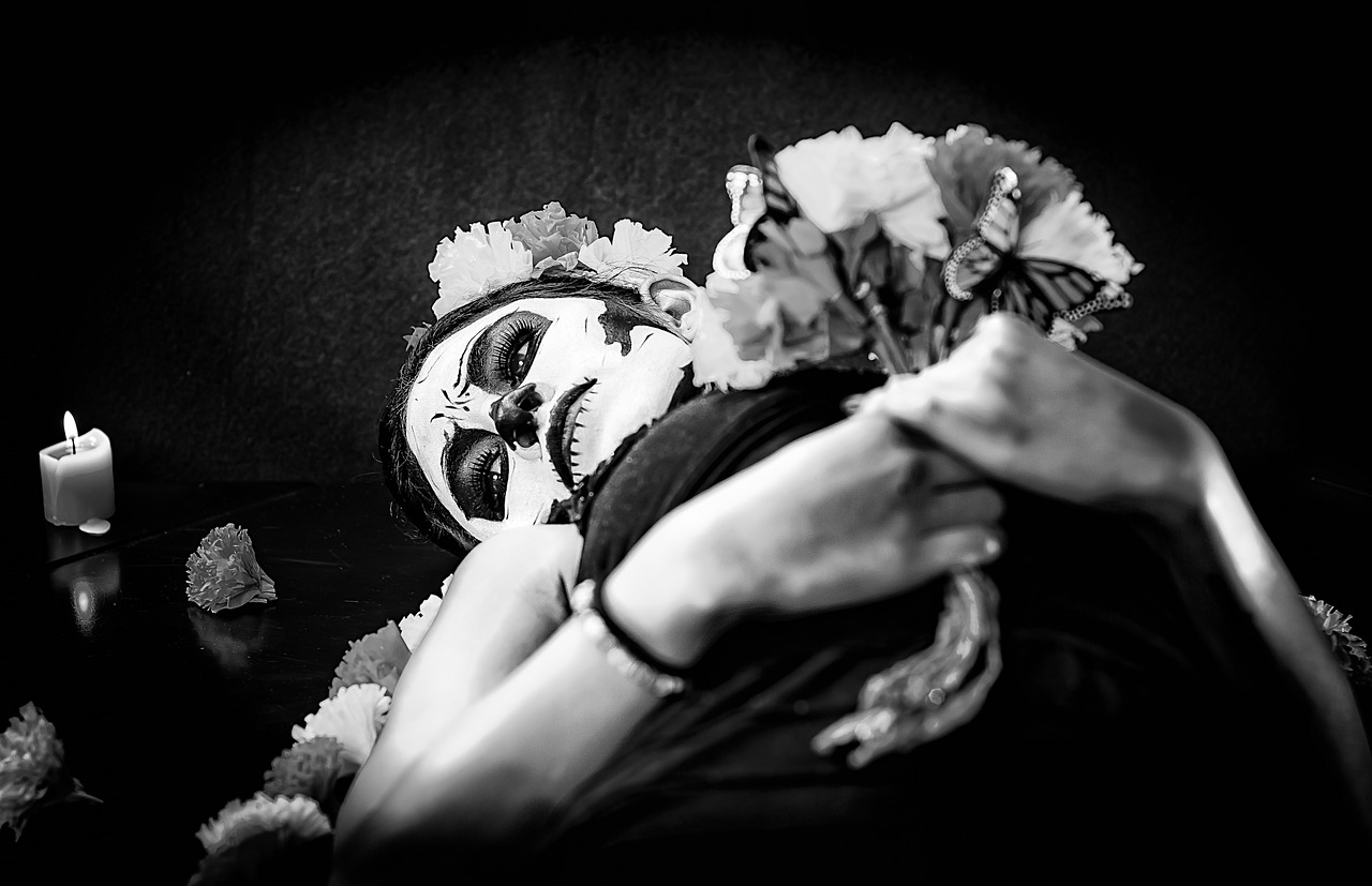 a black and white photo of a person in a clown mask, by Lucia Peka, vanitas, laying on roses, la catrina, pose 1 of 1 6, funeral