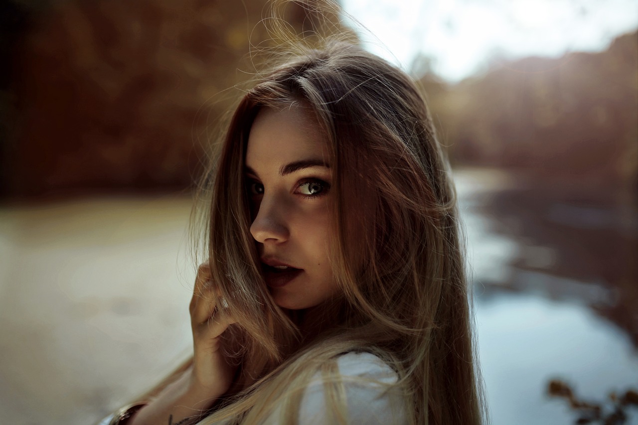 a beautiful young woman standing next to a body of water, a picture, inspired by Elsa Bleda, long blonde hair and big eyes, attractive brown hair woman, ealistic shaded perfect face, close up of a blonde woman