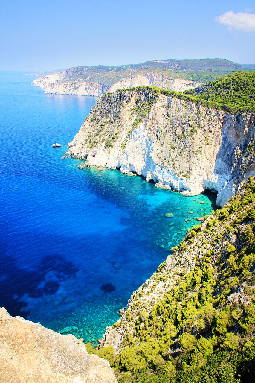 a large body of water next to a cliff, a photo, by Julian Allen, shutterstock, greek nose, blue! and white colors, deep colours. ”, bright sunlight