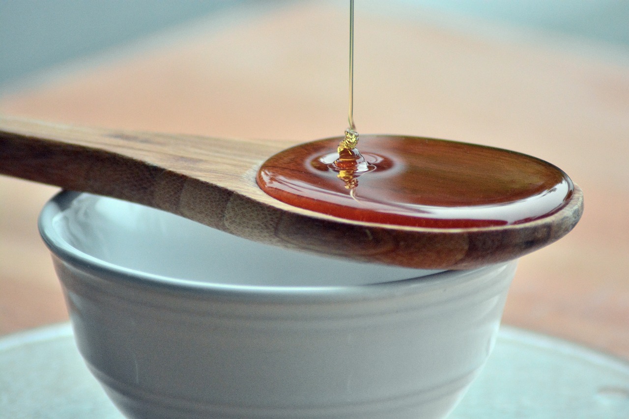 a wooden spoon filled with honey sitting on top of a white cup, by Yi Jaegwan, pexels, olive oil, woodturning, ultrafine detail ”, lacquerware