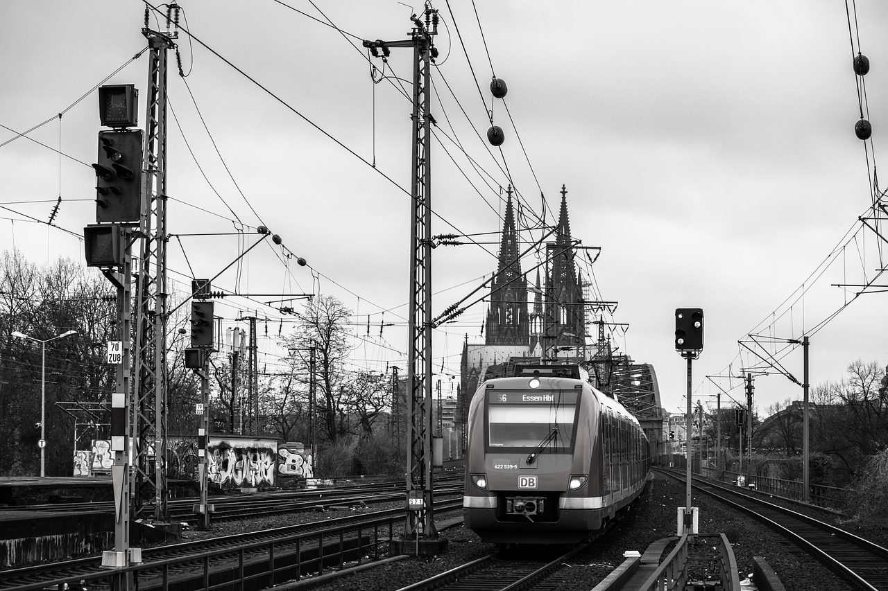 a black and white photo of a train on the tracks, a black and white photo, by Oskar Lüthy, cathedral in the background, electrical signals, middle of the day, markus reugels