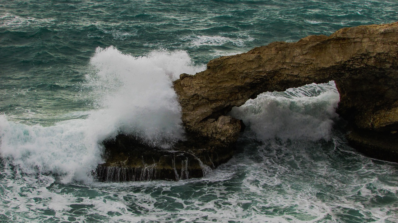 a rock formation in the middle of a body of water, a picture, by Robert Griffier, pexels, romanticism, crashing waves and sea foam, apulia, hurricane, rock arches