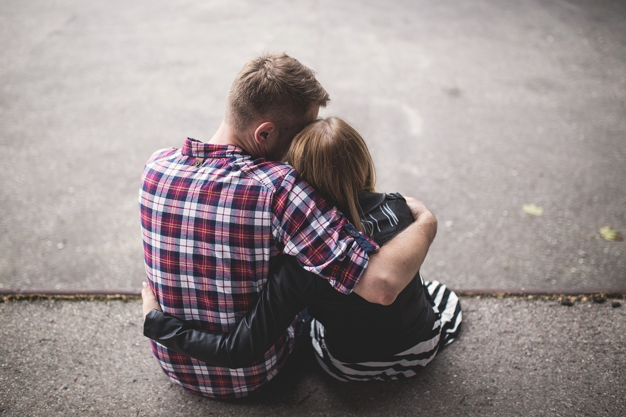 a man and a woman sitting on the ground, a picture, pexels, realism, hug, back turned, striped, holding close