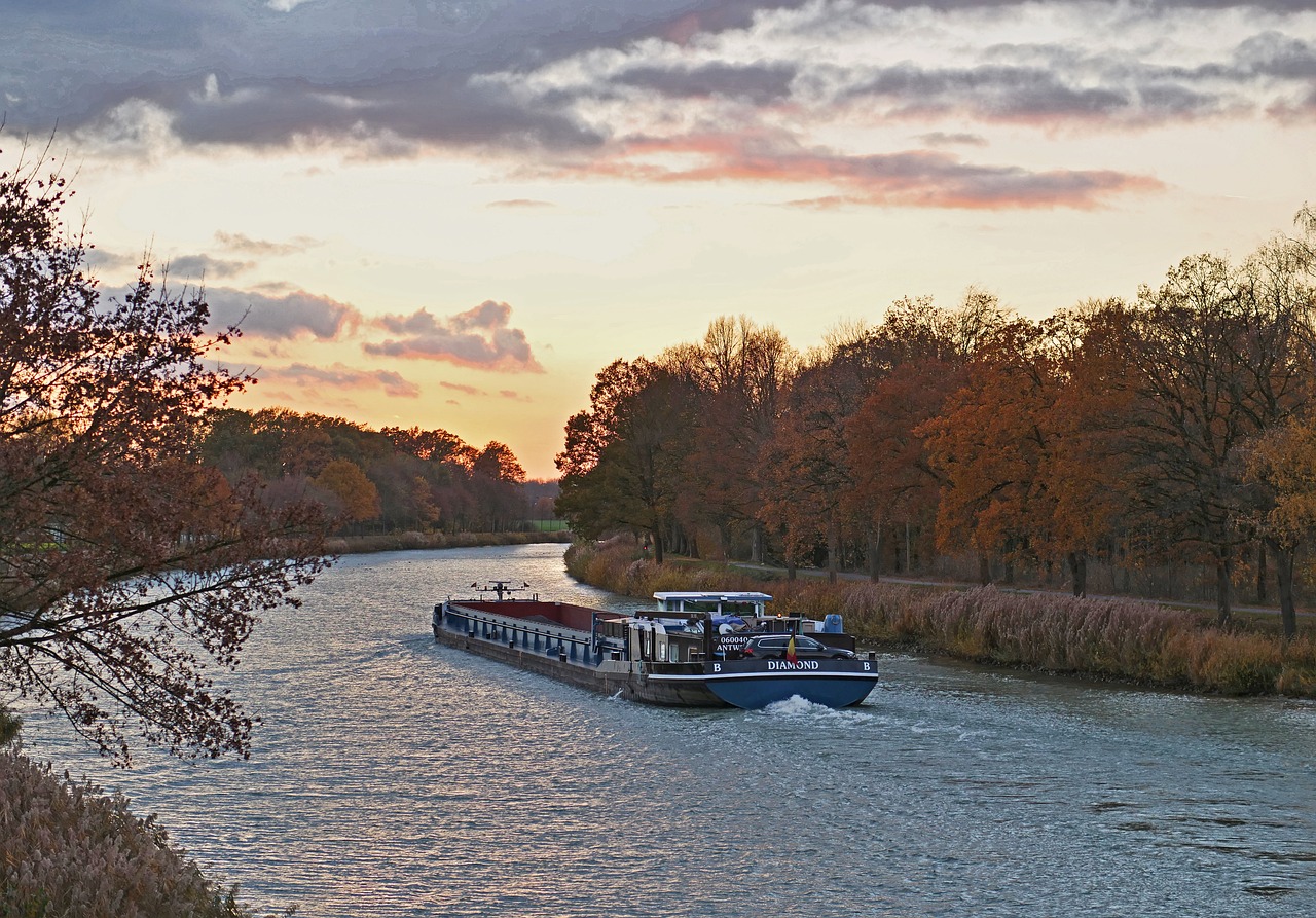 a couple of boats that are in the water, a photo, by Karl Hagedorn, shutterstock, sunset with falling leaves, train, picard on a starboard, blue hour