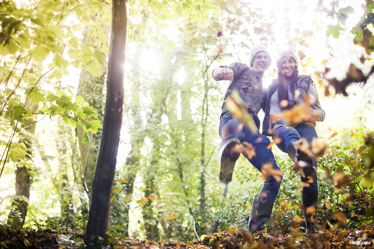 a couple of people that are standing in the woods, happening, flying leaves on backround, istockphoto, happy friend, tight shot