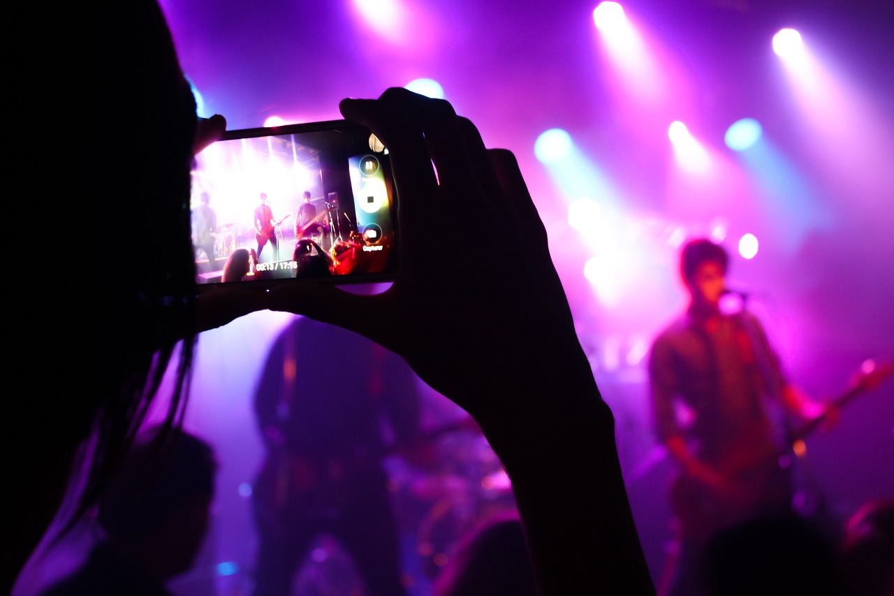 a person taking a picture of a concert with a cell phone, a picture, happening, watch photo, cinematographic photo