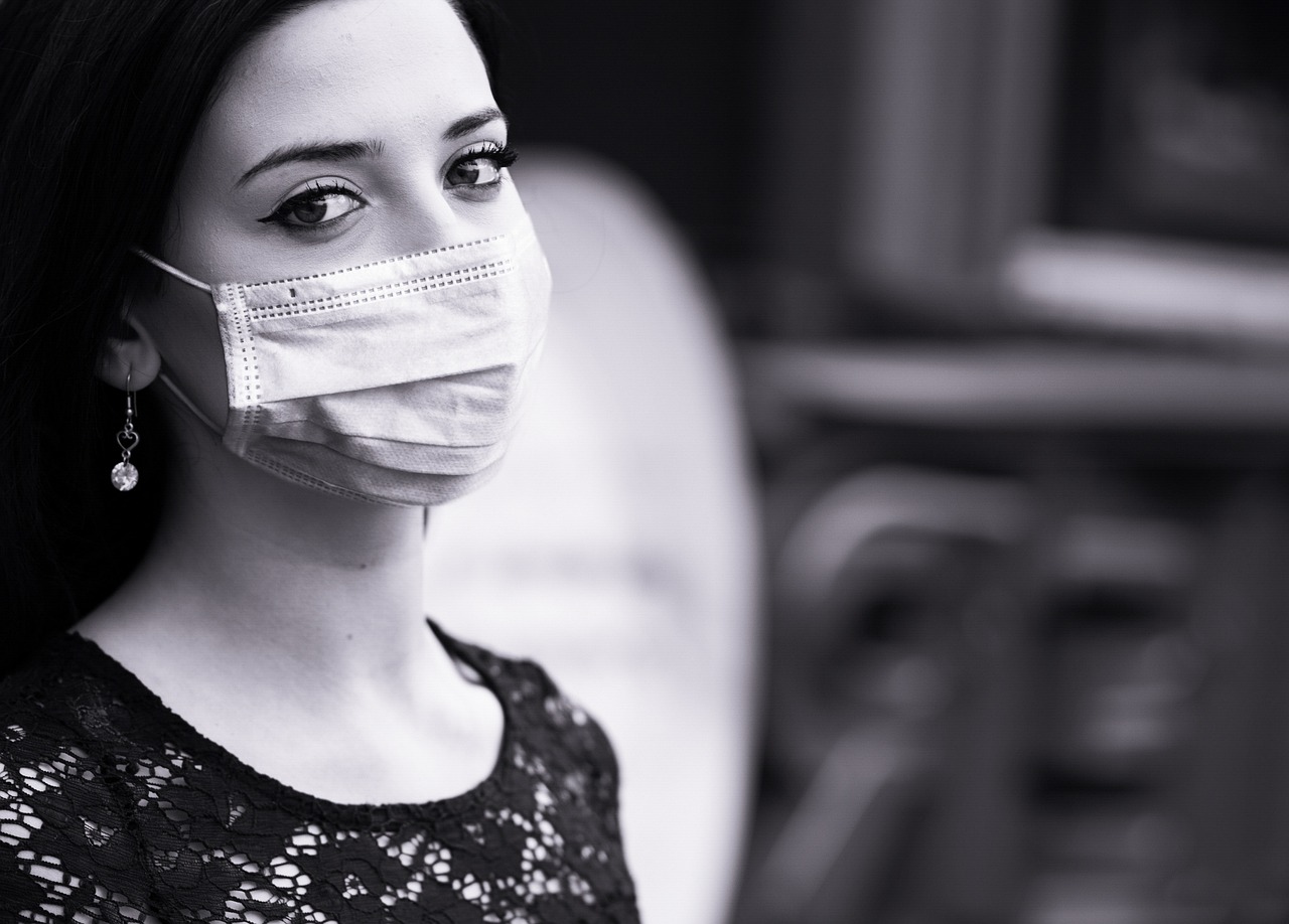 a black and white photo of a woman wearing a face mask, romanticism, sterile background, people watching around, superior look, photo from a promo shoot